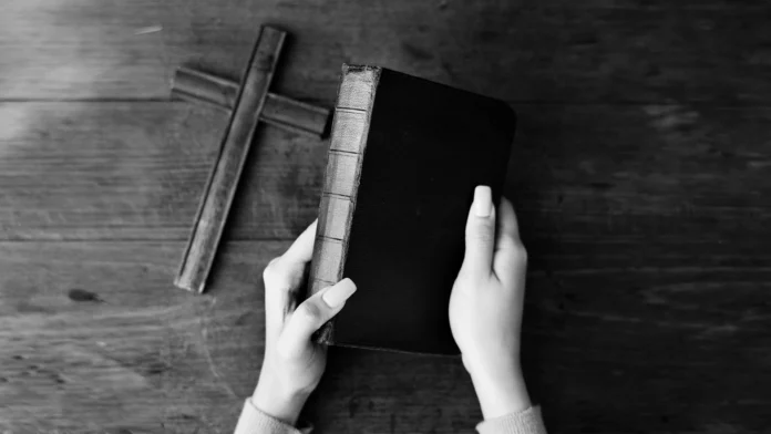 female-hands-holding-bible-wooden-cross